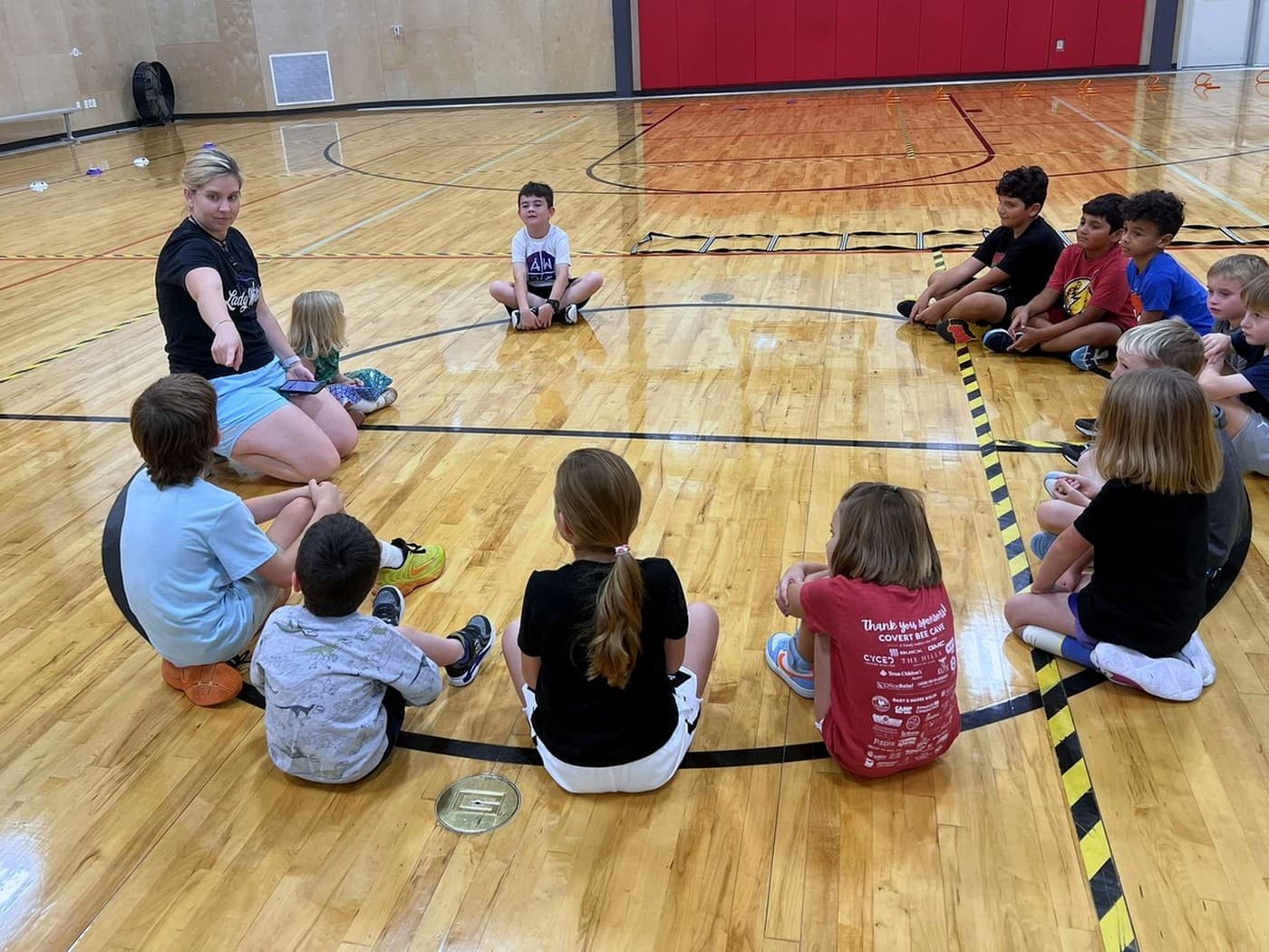ATX Wildcats players sitting in a circle as a coach teaches